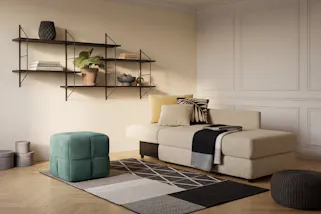 Beiges Schlafsofa zum Ausklappen, dazu ein schwarzes Wandregal und ein grüner Pouf.