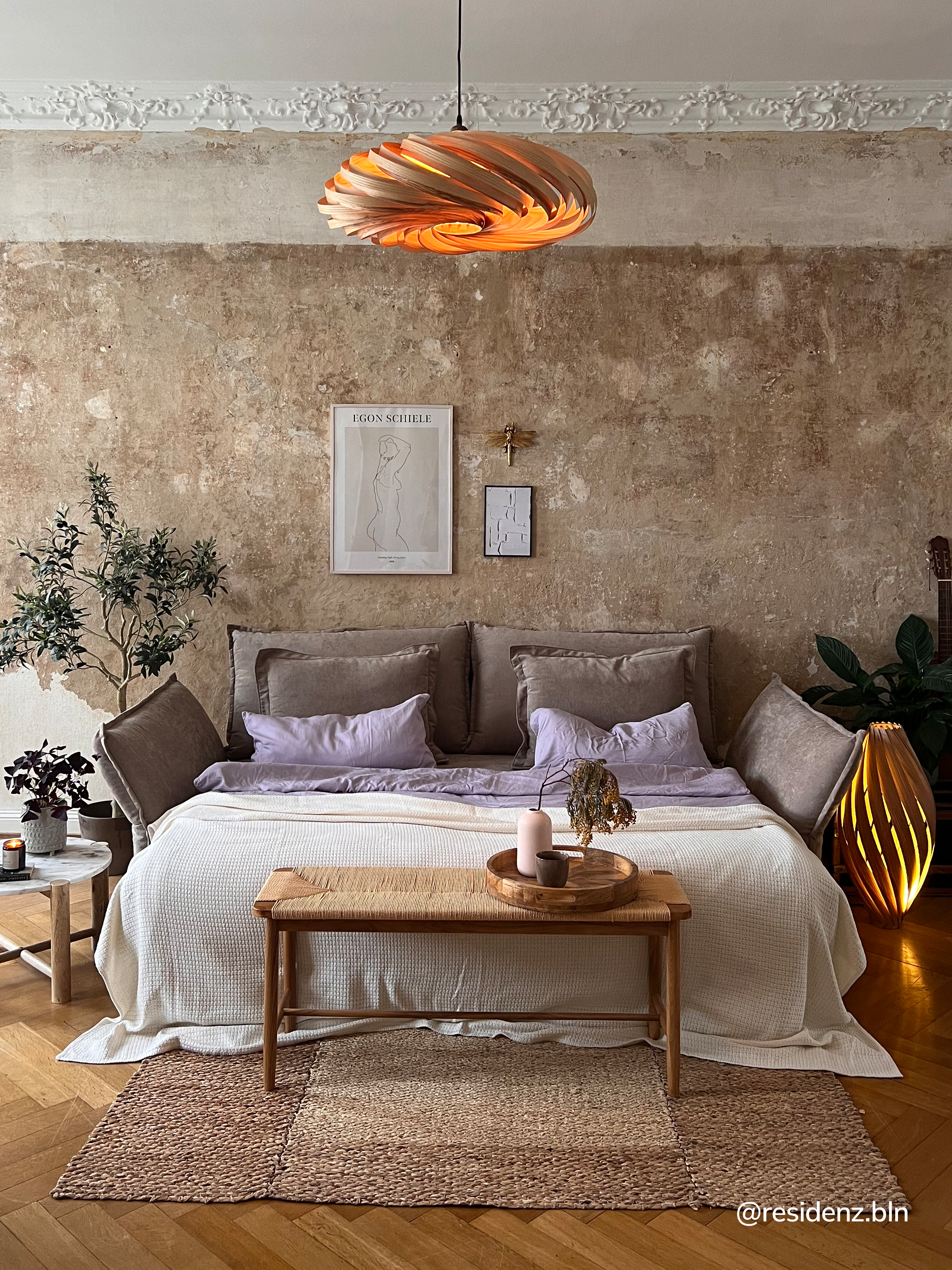 Schlafzimmer in warmen Tönen, strukturierter Wand und Bettbezug in Taupe.