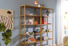 Étagères en bois contre un mur bleu ciel, décorées avec des corbeilles, des livres et des accessoires déco, ainsi qu'une étagère en bois avec des livres et des accessoires de bureau.