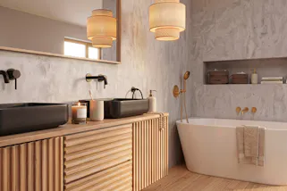 Spa-Ambiente im Badezimmer mit einer frei stehenden Badewanne, einem Waschbeckenunterschrank aus Holz im Lamellenlook sowie mit schwarzen Armaturen, dazu eine schöne Pendelleuchte aus Rattan.