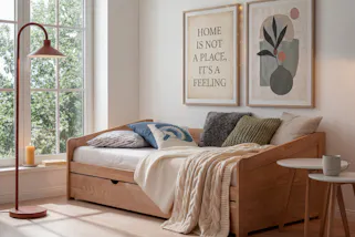 Gästebett aus hellem Holz mit Bettkasten, dazu Beistelltische im Skandi-Stil.