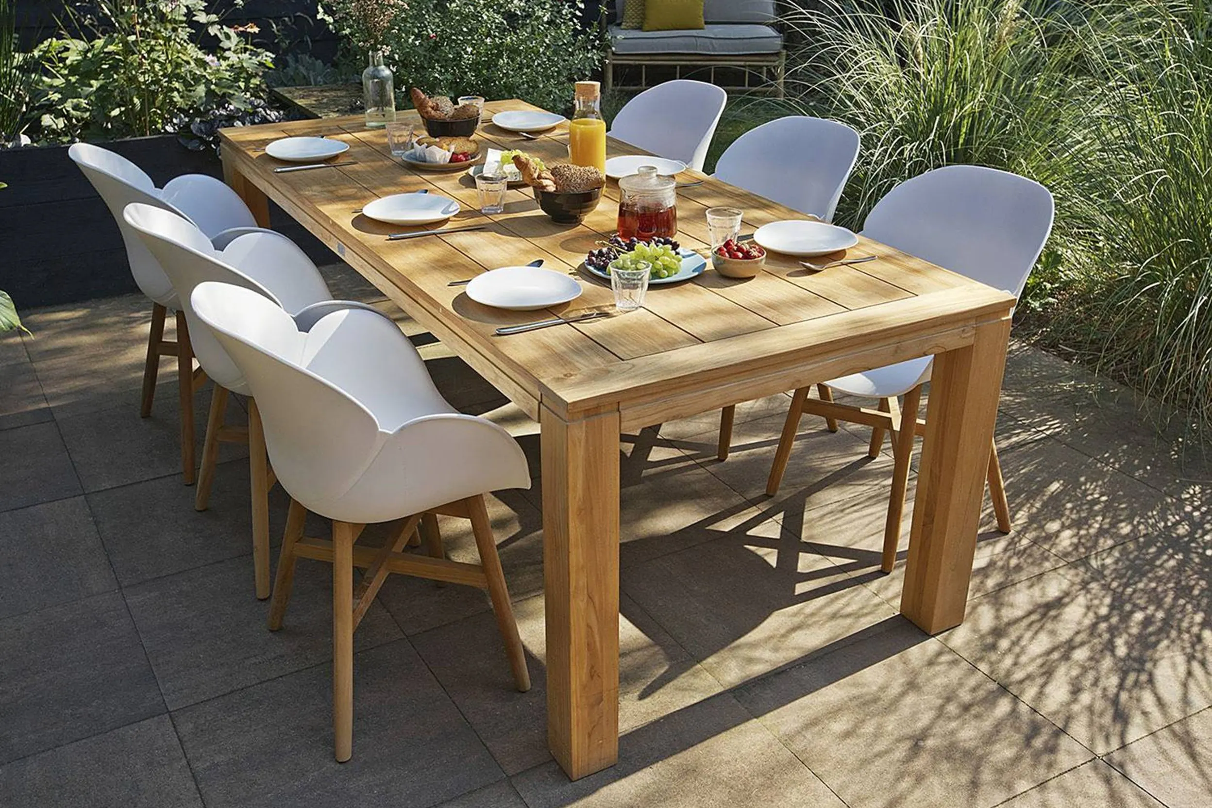 Grosser Holzgartentisch mit sechs Schalenstühlen aus weissem Kunststoff