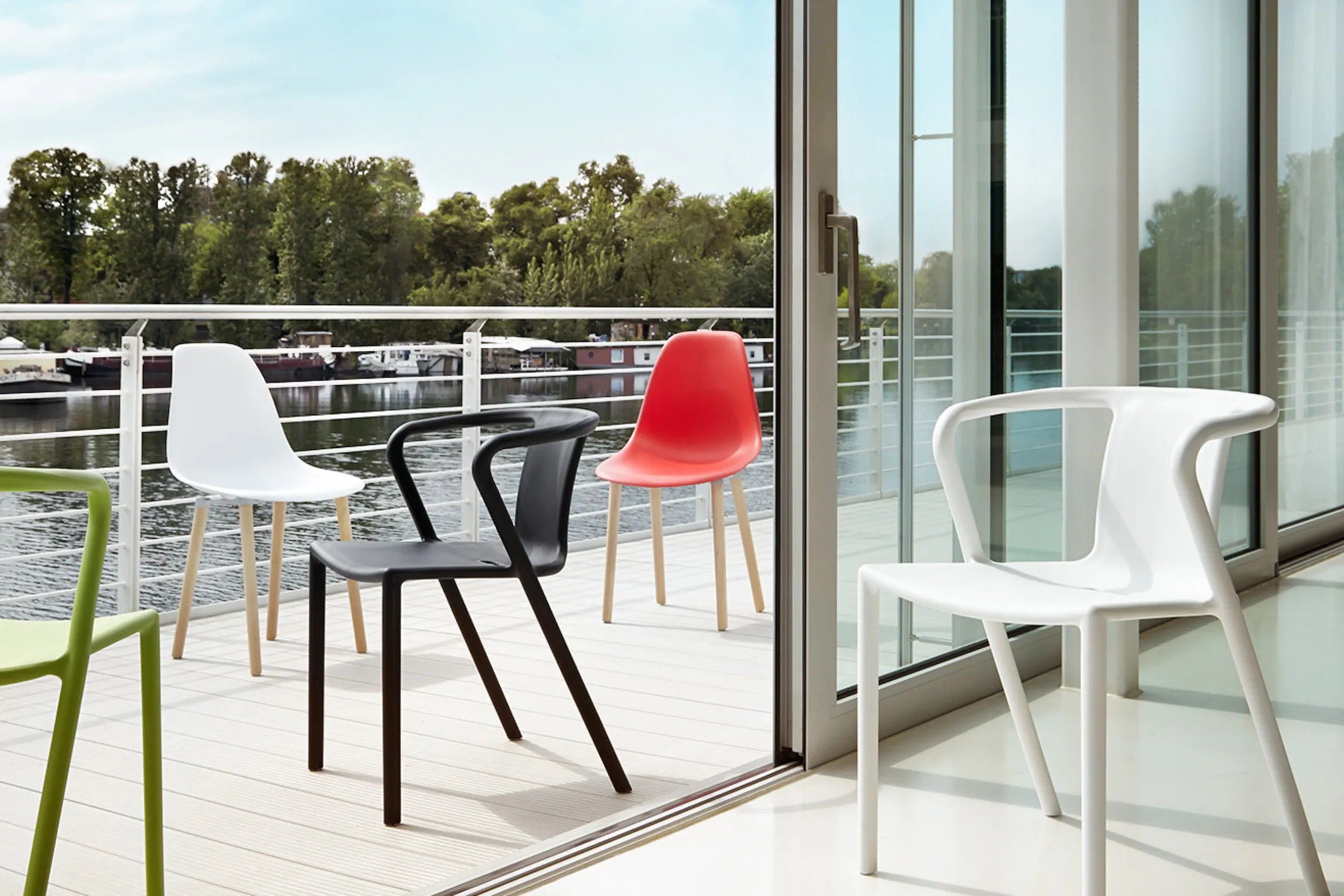 Fünf Kunststoffstühle in verschiedenen Designs und Farben auf einem grossen Balkon