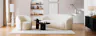 Wohnzimmer in organischen Formen mit Sessel und Sofa Osane in Creme sowie dem schwarzen Couchtisch Besare von Studio Copenhagen, dazu ein weißer Teppich, eine weiße Steh- und Tischleuchte, Keramik- und Holzdeko in Erdtönen sowie ein schwarzes Sideboard.