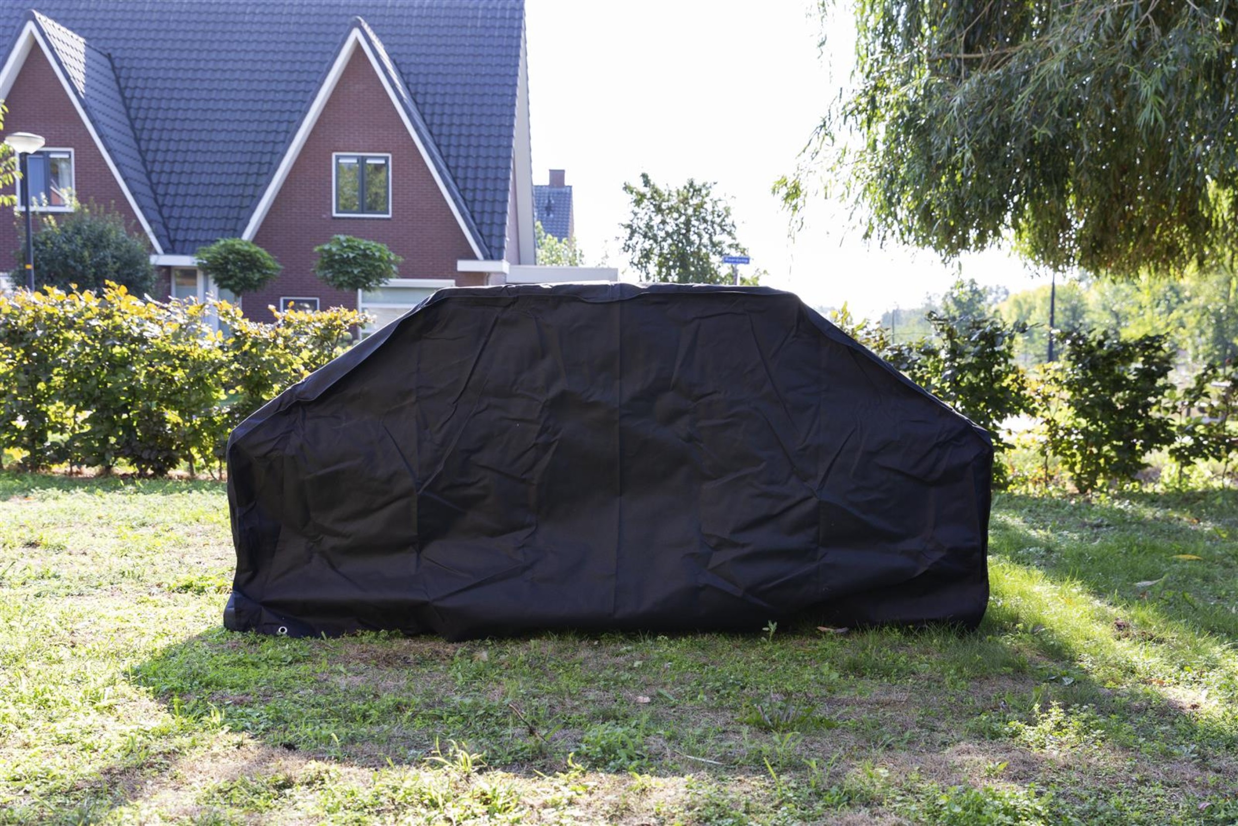 Gartenmöbel im Garten, verpackt unter einer schwarzen Schutzhülle