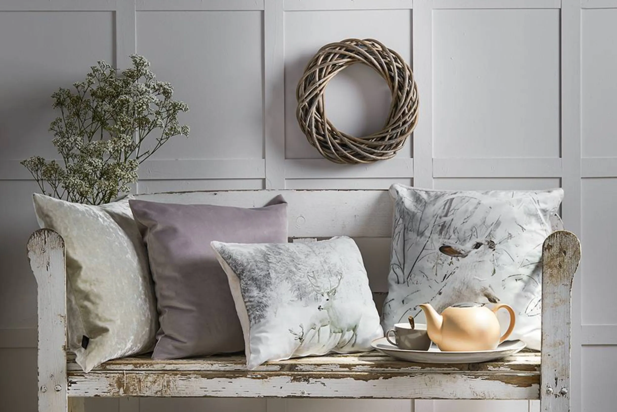 Rustikale Bank mit winterlichen Kissen, Kranz und Trockenblumen