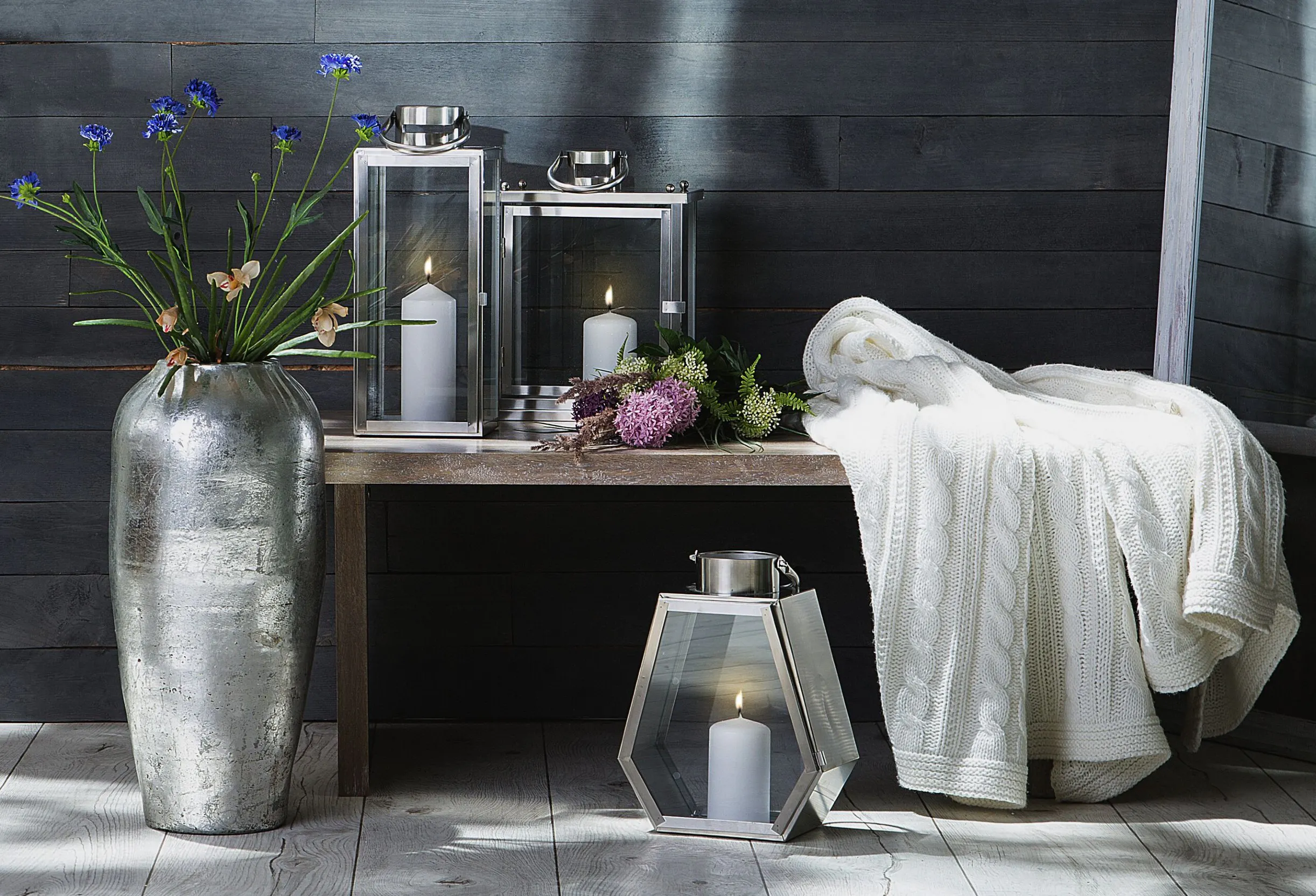 Außenbereich mit silberner Bodenvase, verschiedenen Laternen und weißer Decke