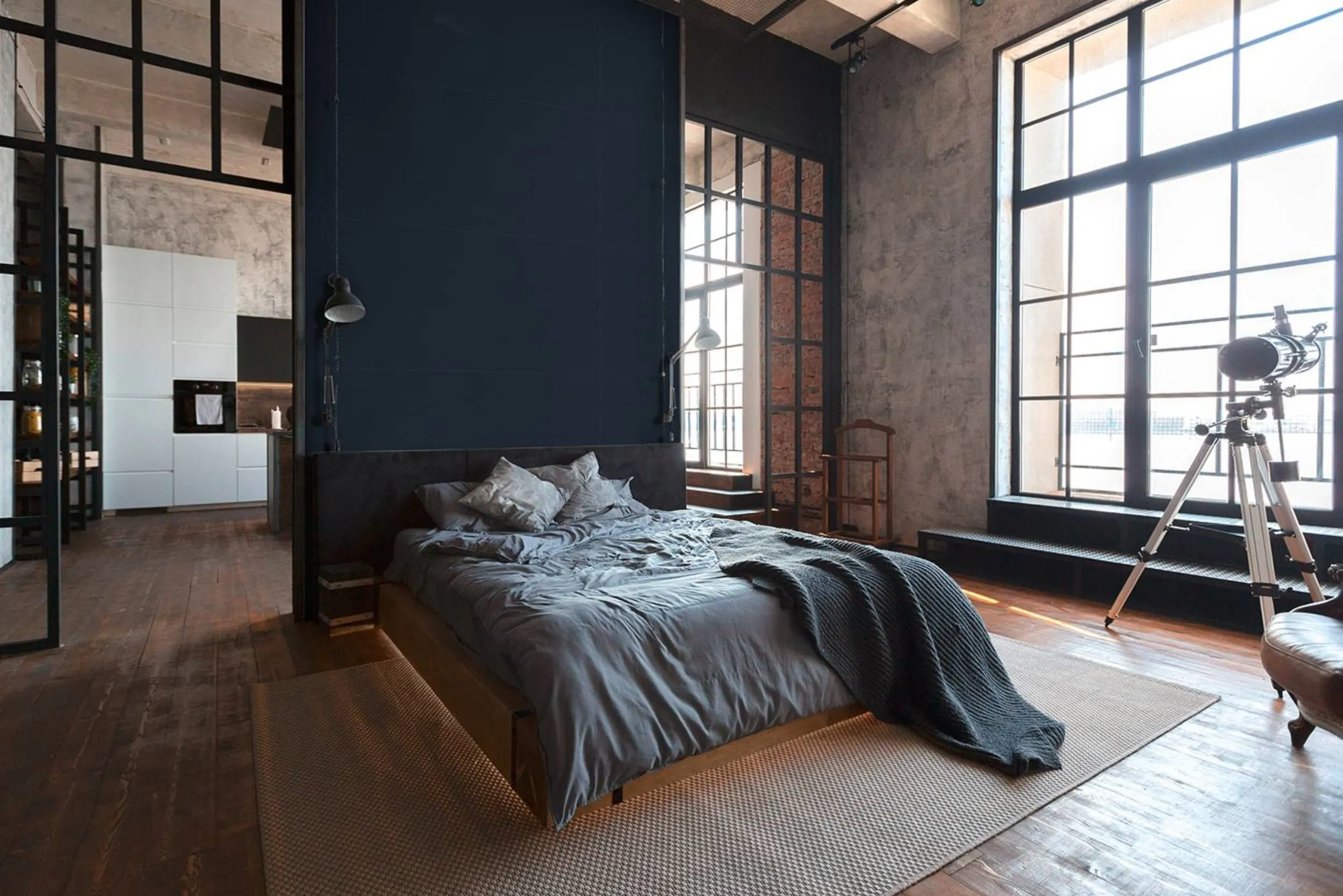 Loft mit schwarzen Fensterrahmen, Bett mit schwarzem Kopfteil und blauer Wand