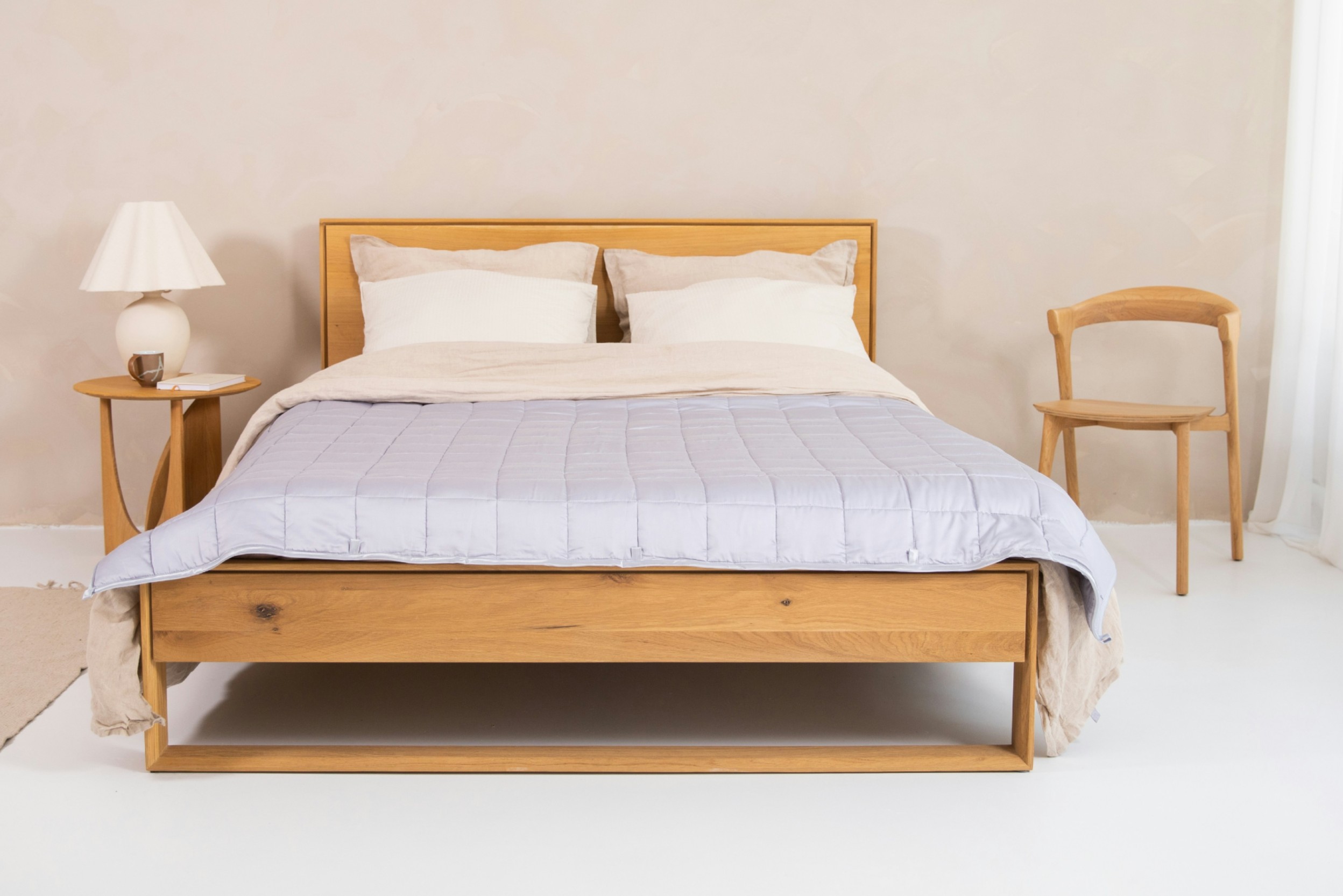 Schlafzimmer mit Holzbett inklusive Bettdecke und Kissen, Stuhl und Nachttisch