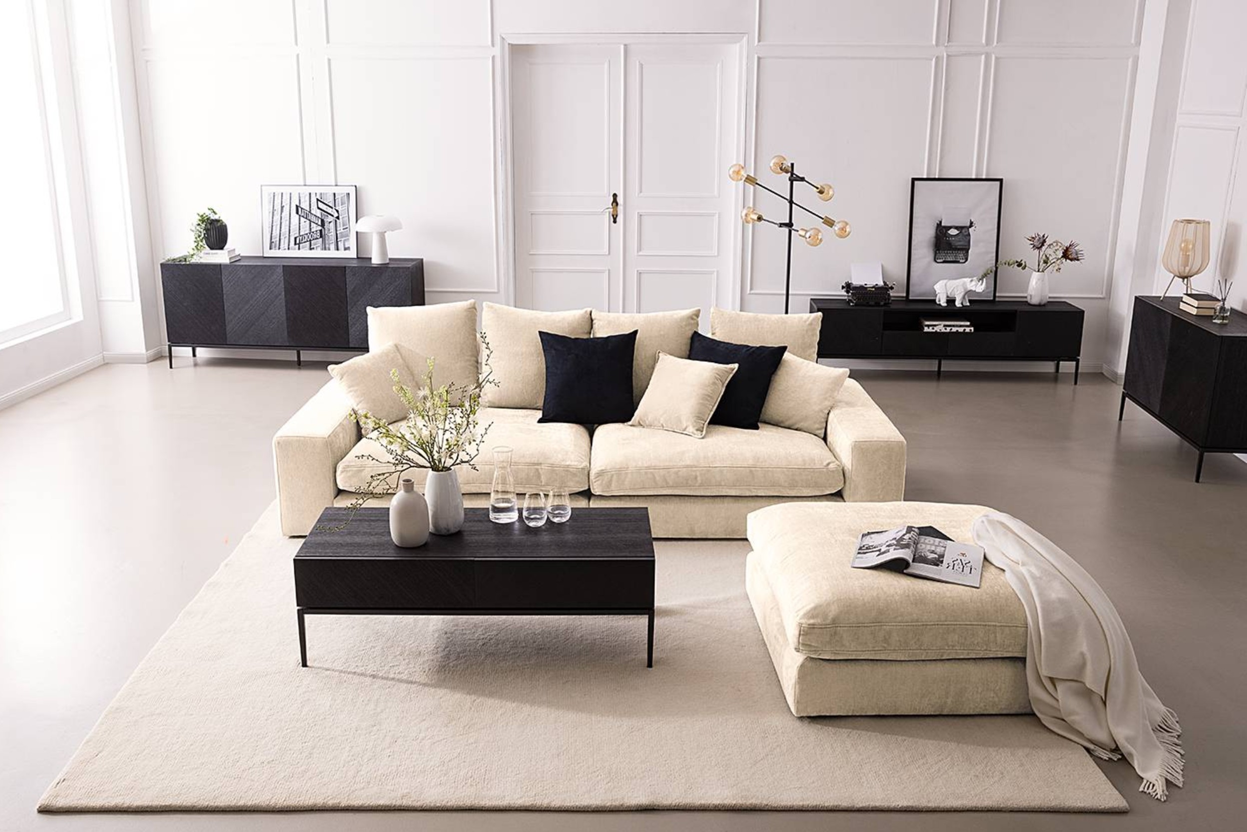 Wohnzimmer mit beiger Couch, beigem Teppich und schwarzen Möbeln