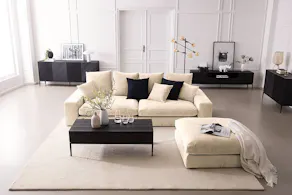 Wohnzimmer mit beiger Couch, beigem Teppich und schwarzen Möbeln
