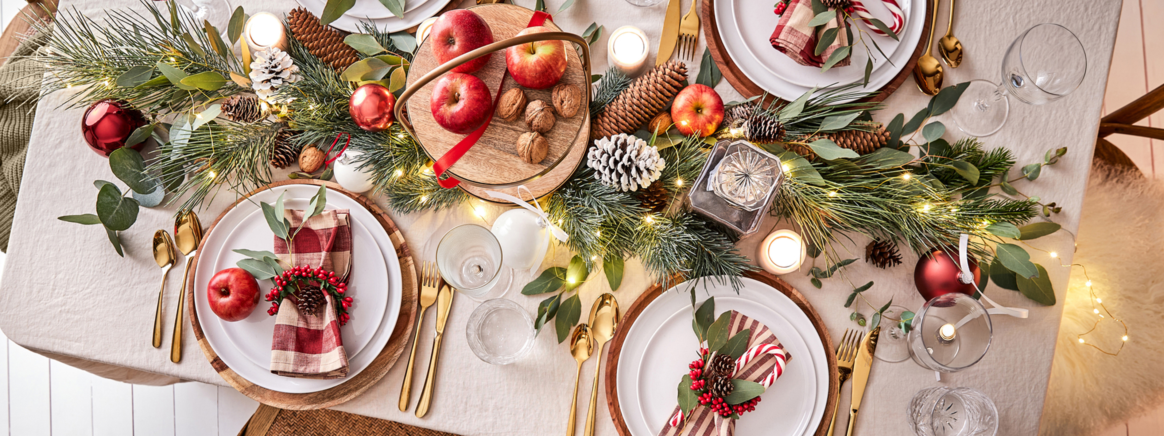Table dressée pour Noël dans un style traditionnel avec du rouge, du doré et du bois.
