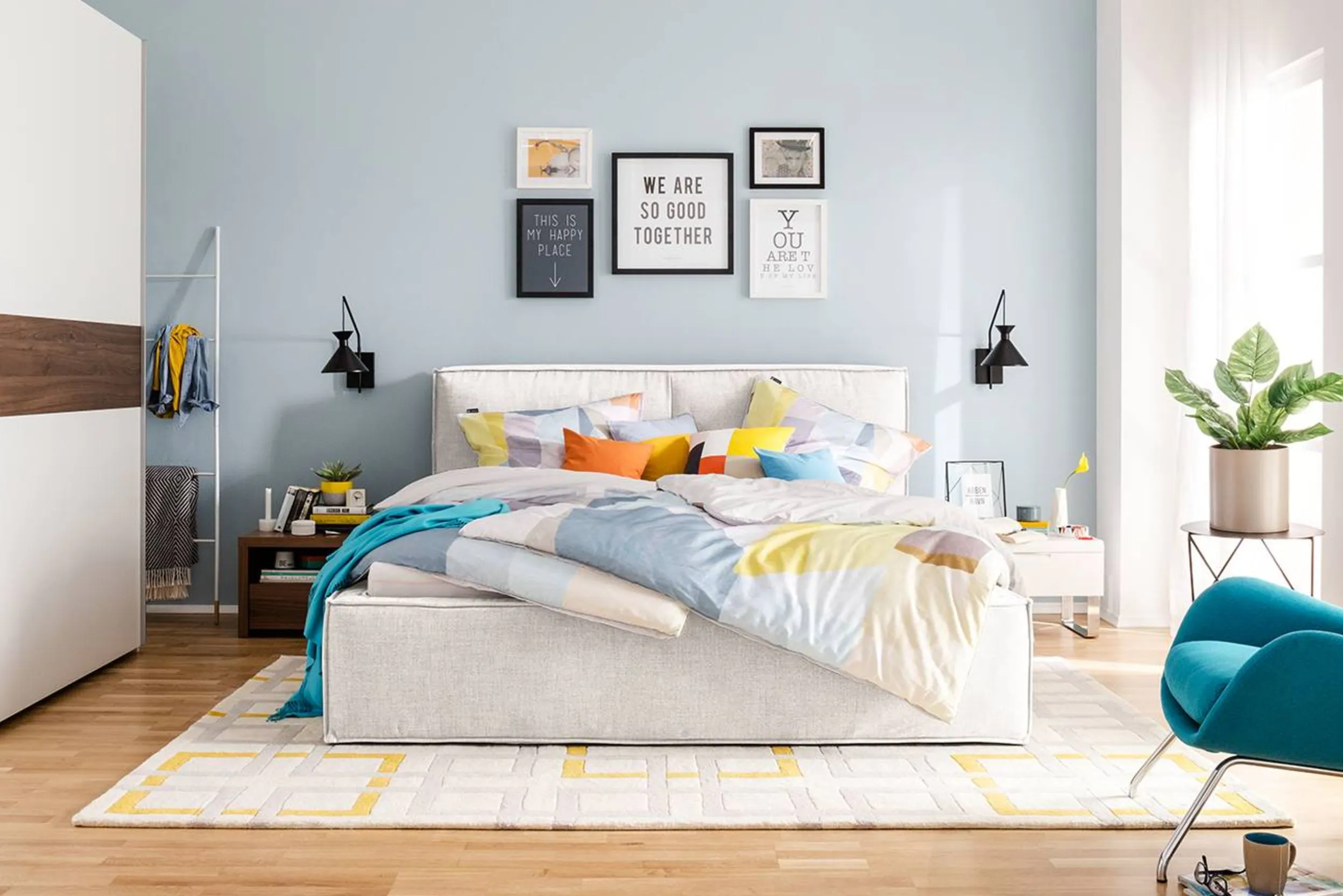 Modernes Schlafzimmer mit hellem Polsterbett, weißer Bettwäsche und bunten Kissen