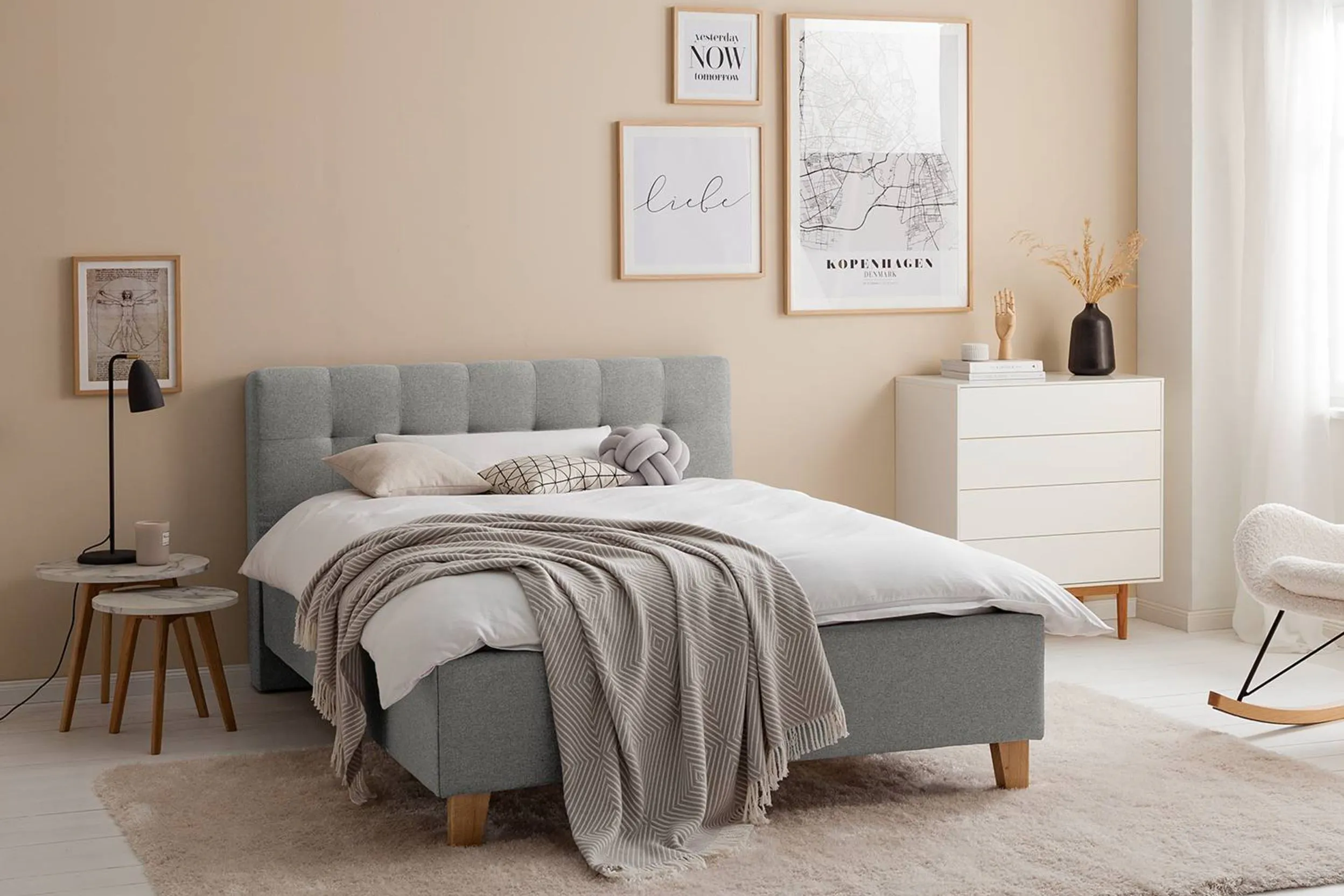 Minimalistisches Zimmer mit hellgrauem Bett und beiger Wand