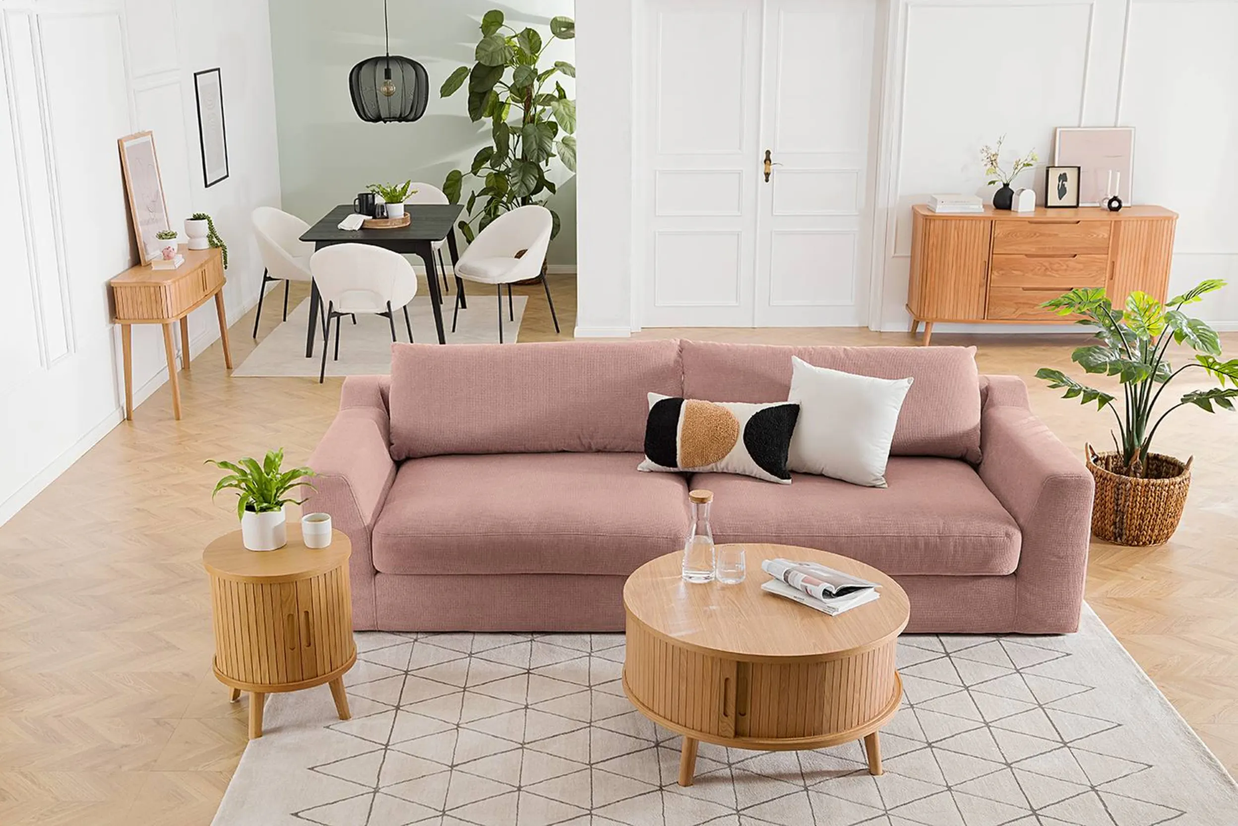 Wohnbereich mit rosa Couch, dahinter Essbereich mit schwarzem Tisch und weißen Stühlen