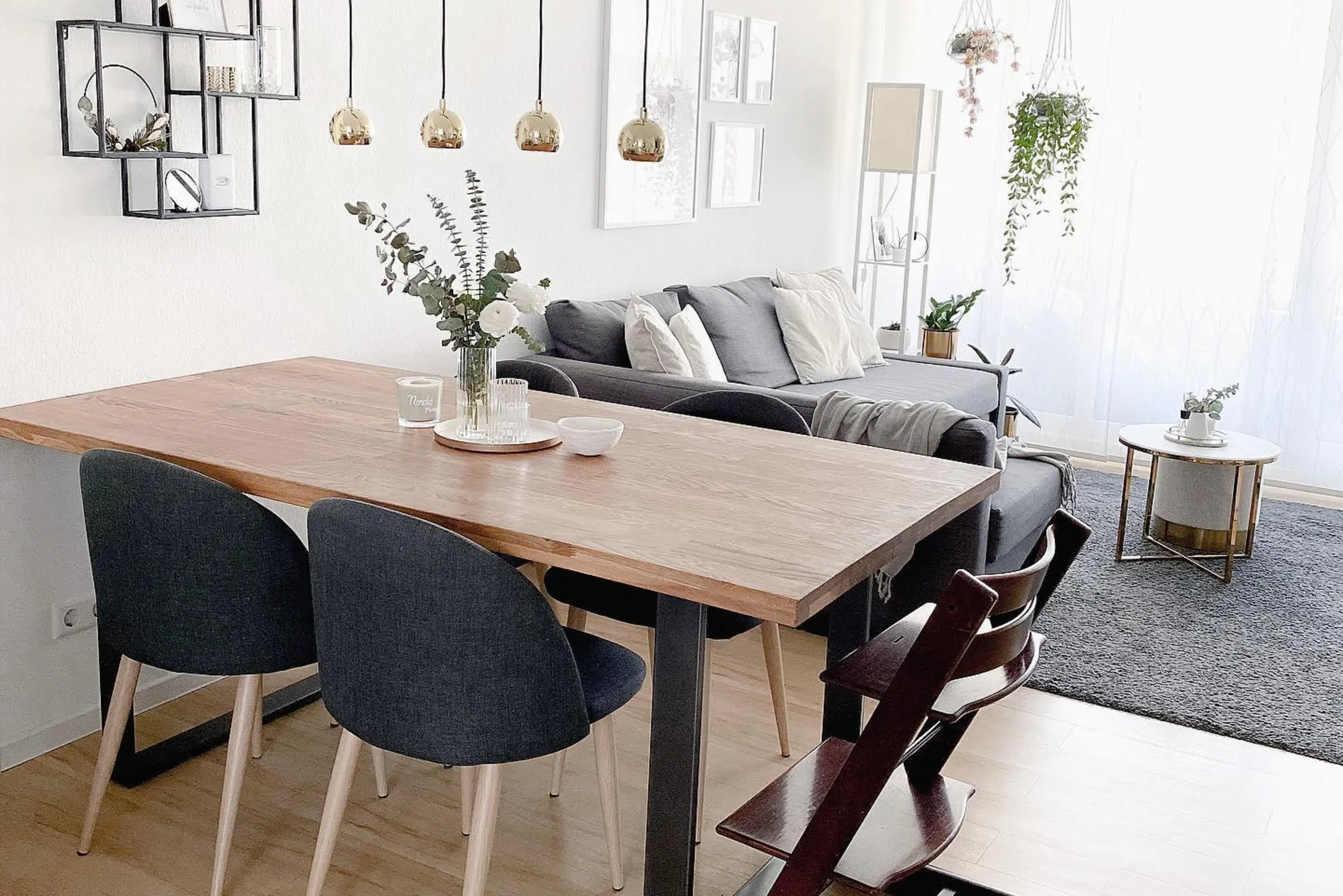 Essbereich mit mehrflammiger Pendelleuchte, im Hintergrund Couch-Bereich mit weißer Stehlampe