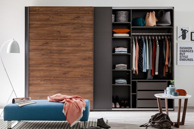 Braun-schwarzer Kleiderschrank mit Schwebetür und einer blauen Bank davor