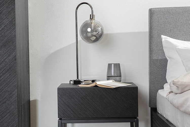 Nachttischlampe mit grauem Kugelglas auf einem schwarzen Nachttisch