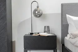 Nachttischlampe mit grauem Kugelglas auf einem schwarzen Nachttisch