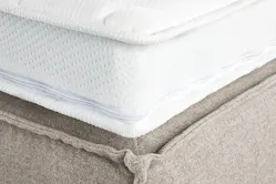 Detailbild eines Matratzen-Toppers auf einem beigen Bett