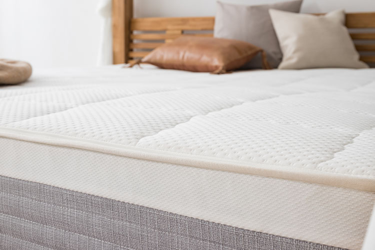 Detailbild einer Matratze auf einem grauen Bett