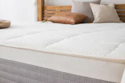 Detailbild einer Matratze auf einem grauen Bett