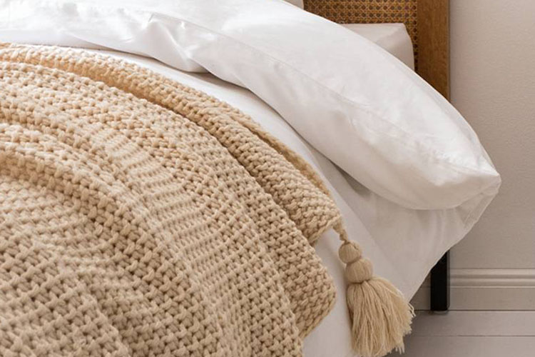 Hellbraune Tagesdecke, die locker über ein Bett mit weißer Bettwäsche