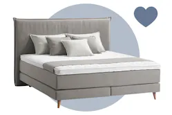 Graues Boxspringbett Avellino mit passenden grauen Kissen und Tagesdecke
