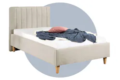 Beiges Einzelbett mit gepolstertem Kopfteil vor einem blau illustierten Kreis