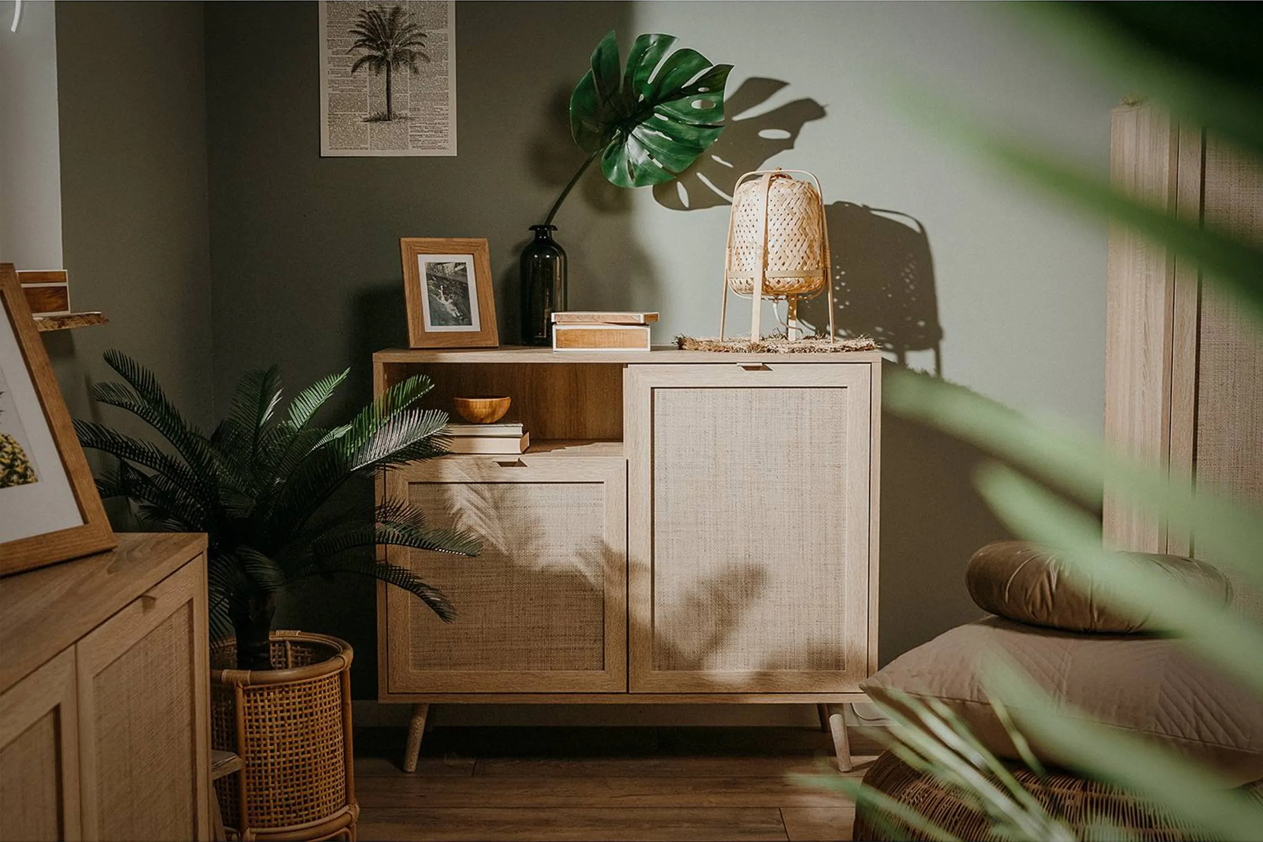 Skandinavische Holzkommode mit Zimmerpflanzen vor einer grünen Wand