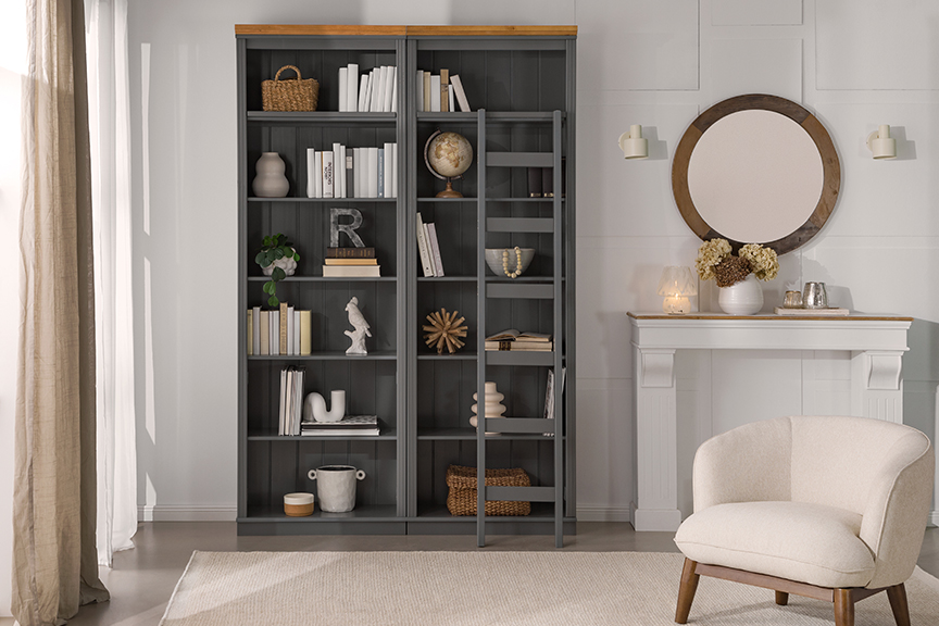 Lesezimmer bzw. eigene Heimbibliothek im Wohnzimmer mit großer Bücherwand inklusive Regalleiter, einladenden Lesesesseln und Sofas sowie gemütlichen Textilien und Deko.