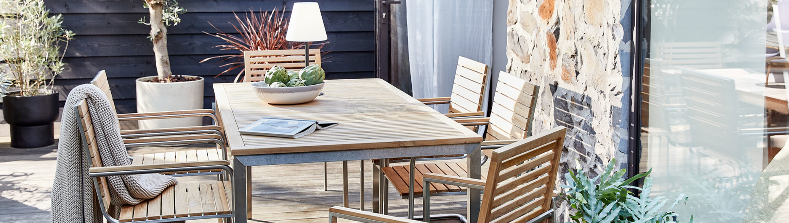 Terrasse mit einem Gartentisch, Gartenstühlen und Outdoorfreischwingern der Serie Teakline aus hochwertigem Teakholz und Edelstahl.