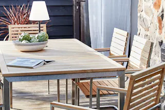 Terrasse mit einem Gartentisch, Gartenstühlen und Outdoorfreischwingern der Serie Teakline aus hochwertigem Teakholz und Edelstahl.