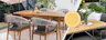 Moderne Terrasse mit einer Outdoor-Lounge aus Teakholz und Edelstahl von der BUTLERS Möbelserie Teakline, dazu gemütliche Textilien wie Kissen und ein Outdoor-Teppich sowie weitere Gartenaccessoires; daneben ein Detailbild eines Outdoor-Tischs aus Teakholz.