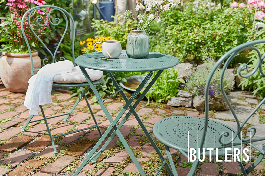 Garten-Set von Butlers in Salbeigrün bestehend aus zwei Metallstühlen mit verschnörkelter Rückenlehne und einem runden Tisch aus Metall