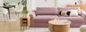 Offener Wohn- und Essbereich mit dem Trend-Bigsofa Dixwell von home24 als Ankerpunkt, dazu Stauraummöbel aus hellem Holz im Retro-Stil sowie ein schwarzer Esstisch, schwarz-weiße Esszimmerstühle, Teppiche, schwarze Lampen und Grünpflanzen.