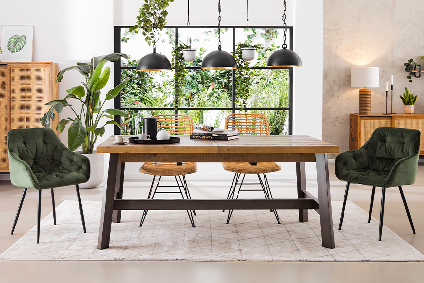 Esszimmer mit Loft-Charakter und viel Platz für einen Auszieh-Esstisch, verschiedene Stühle aus Samt und Rattan, Massivholzschränke sowie allerlei tropische Pflanzen und trendige Designerlampen.