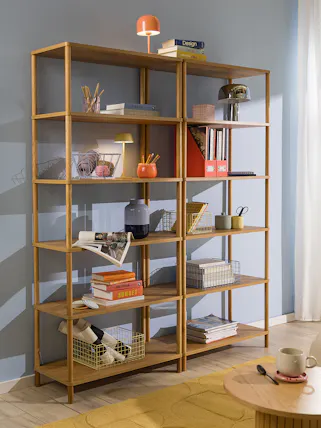 Modernes Standregal aus Holz vor himmelblauer Wand, dekoriert mit Körben, Büchern und Deko, dazu ein Holzregal mit Büchern und Schreibartikeln.