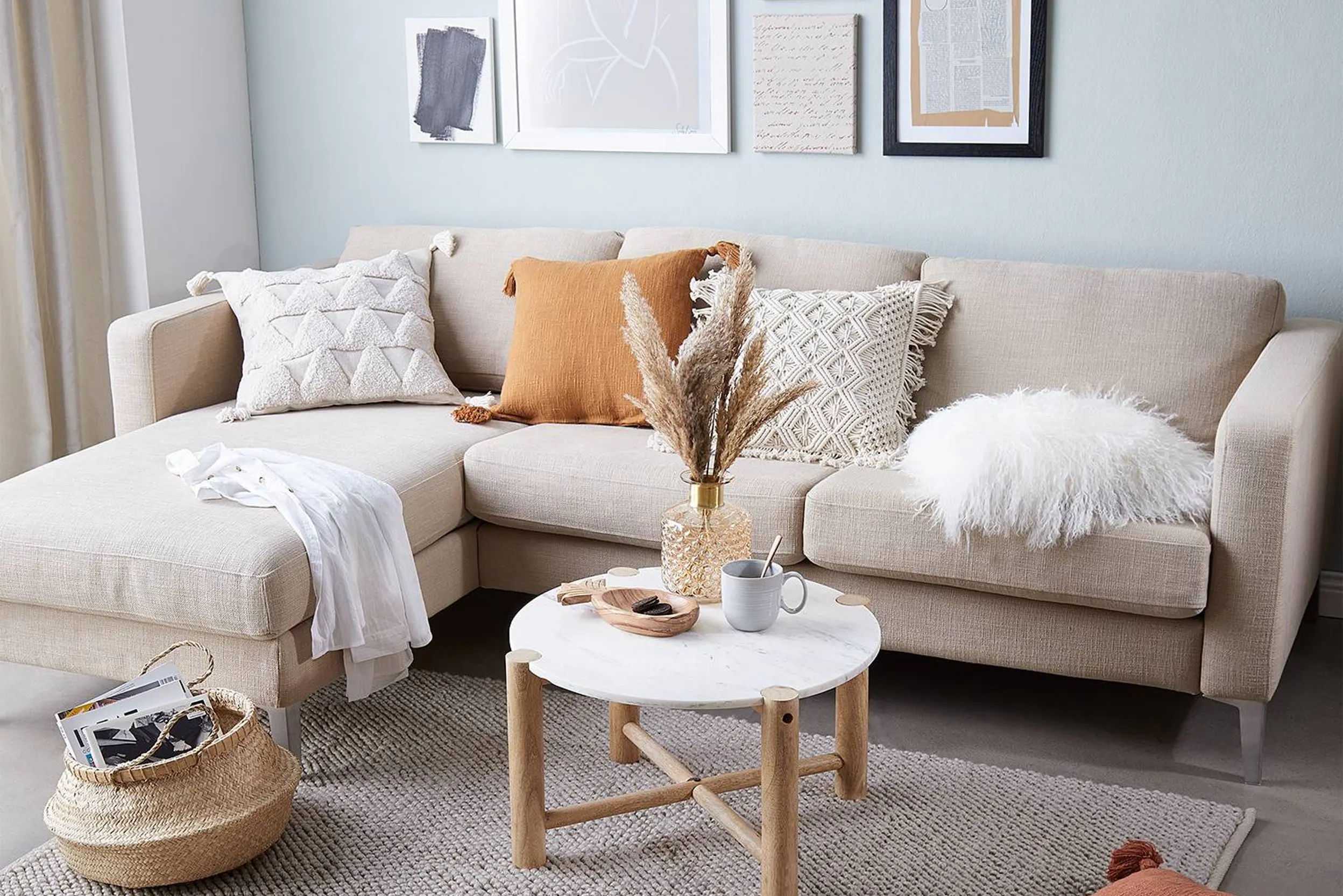 Kleines Wohnzimmer in hellen Tönen mit beigem Eecksofa und kleinem Tisch