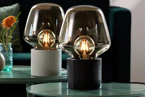 Zwei Tischlampen mit Betonfuß und Glasschirm.