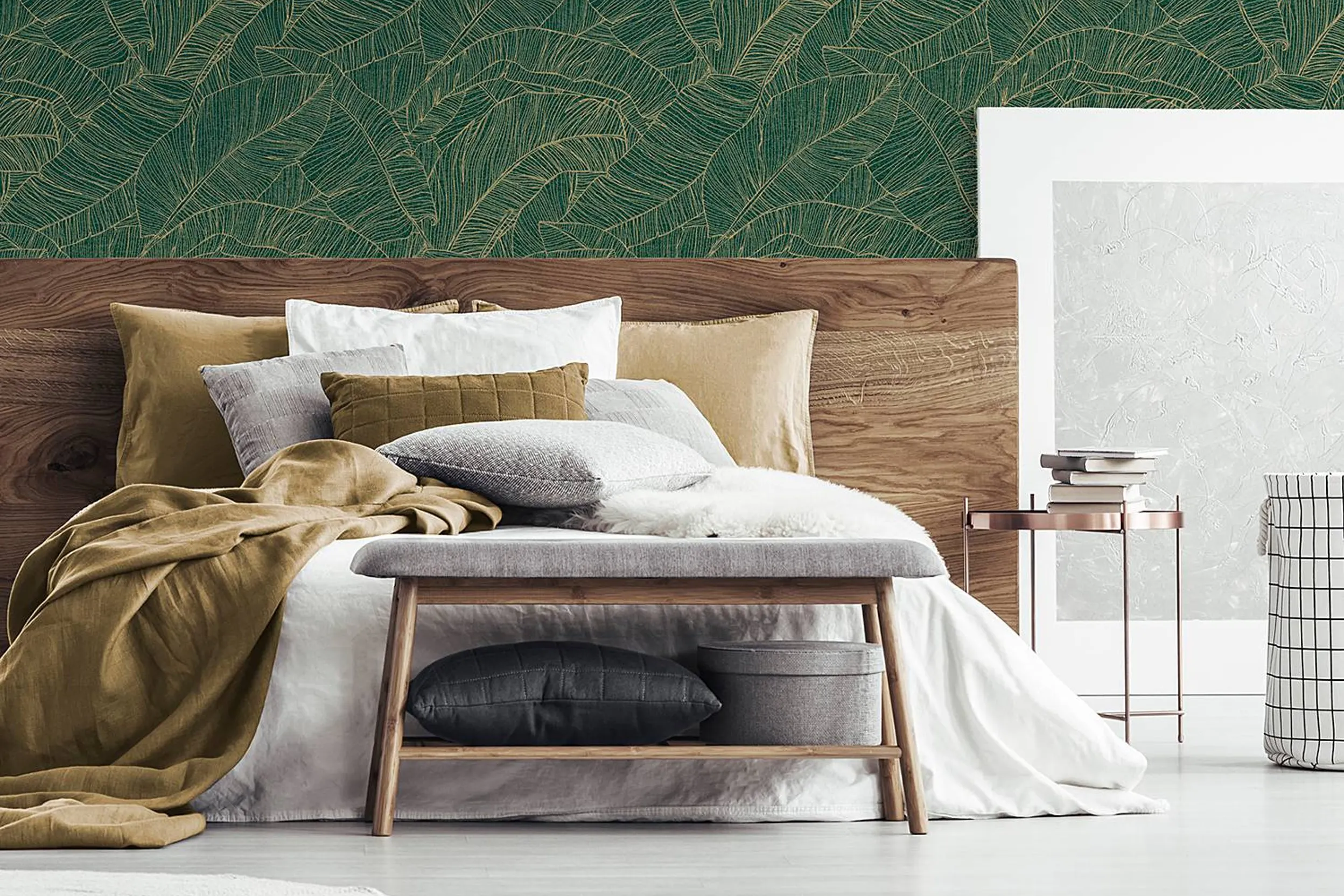Holzbett mit Bettbank mit goldenen Textilien vor gold-grüner Tapete