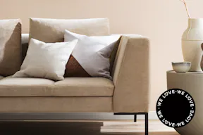 Une décoration beige déclinant toutes les nuances, du crème au sable, en passant par la vanille, l'ivoire, l’écru, le taupe et un blanc cassé lumineux. Un canapé sobre ton sur ton, assorti au mur, avec des coussins et des accessoires dans des teintes similaires. À côté, une chambre chaleureuse ornée de décorations naturelles et de textiles variés.