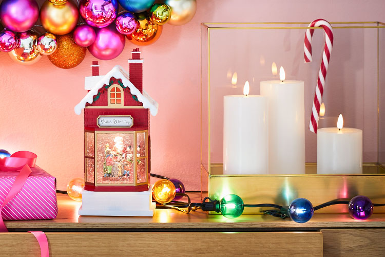 Weihnachtsdeko in pinken Farbtönen mit einem roten Lichterhaus und Laternen mit weißen Kerzen