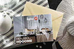 home24 Geschenkgutschein mit Weihnachtsmotiv auf einem schwarzen Tisch mit Weihnachtsgeschenken und -deko in Silber und Weiß
