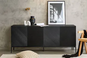 Schwarzes Sideboard mit vier Türen aus der Serie Ikon by Studio Copenhagen von einer Wand aus Sichtbeton, gestylt mit Vasen in modernen Formen sowie einer gerahmten Schwarz-Weiß-Fotografie.