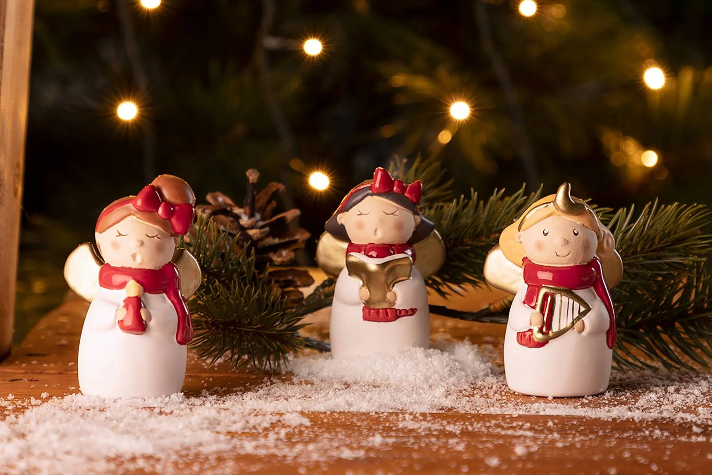 Drei singende Weihnachtsfiguren vor einem Christbaum