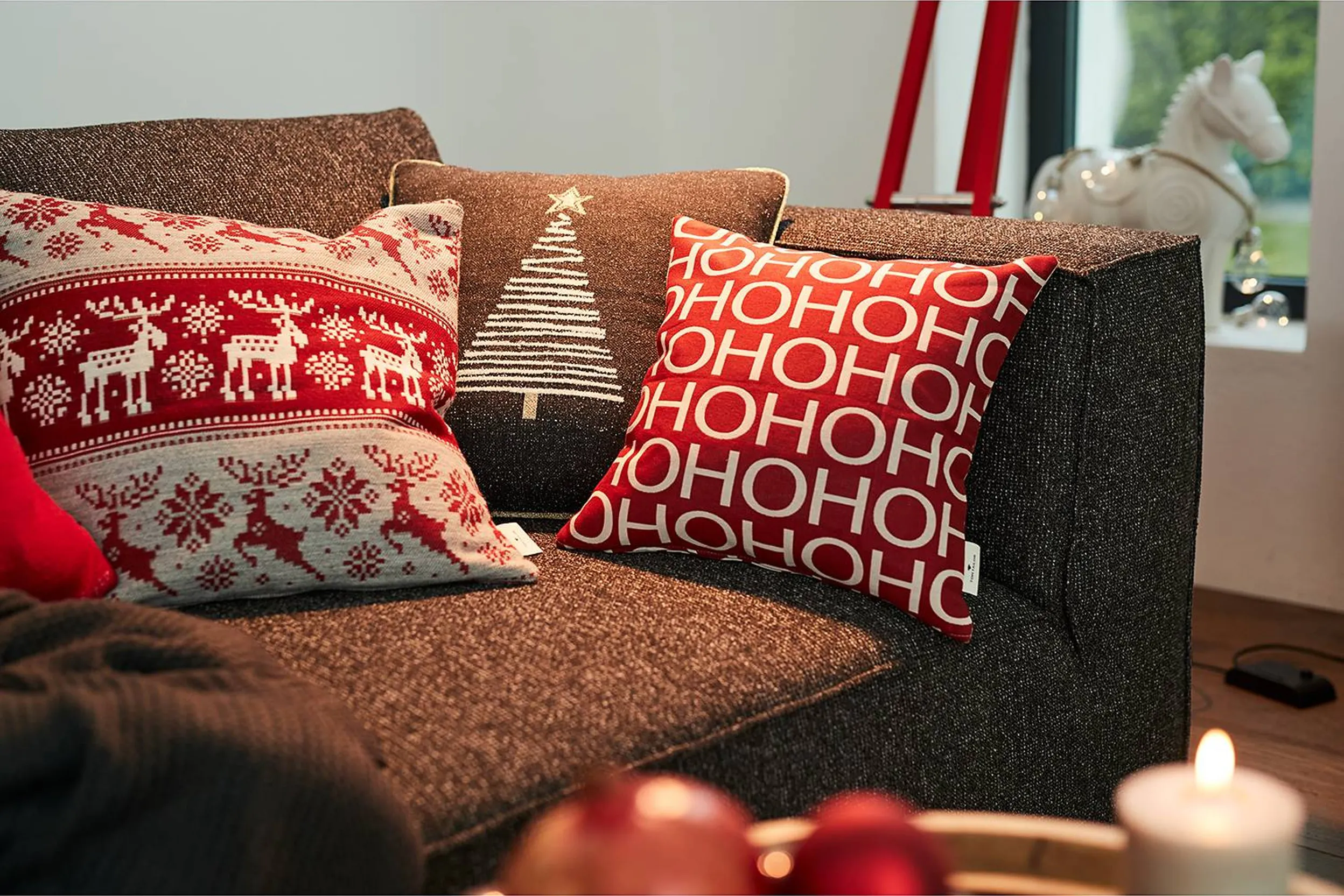 Sofa dekoriert mit drei weihnachtlichen Kissen in Rot, Weiß und Grau