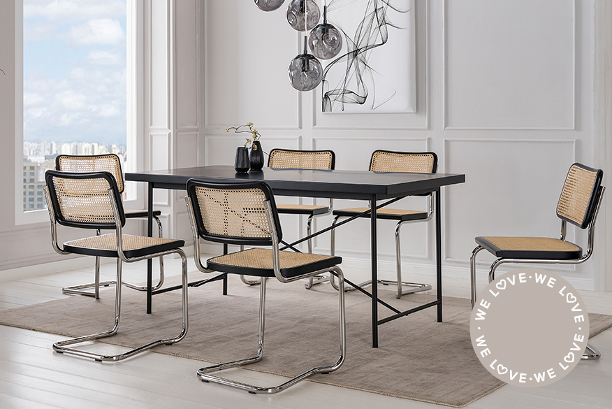 Esstisch aus hellem Holz kombiniert mit Freischwingern mit silbernem Rohrgestell und einer Sitzfläche aus Wiener Geflecht und schwarzen Akzenten vor einer grau marmorierten Tapete; daneben ein grauer Sessel mit Stahlrohrgestell.