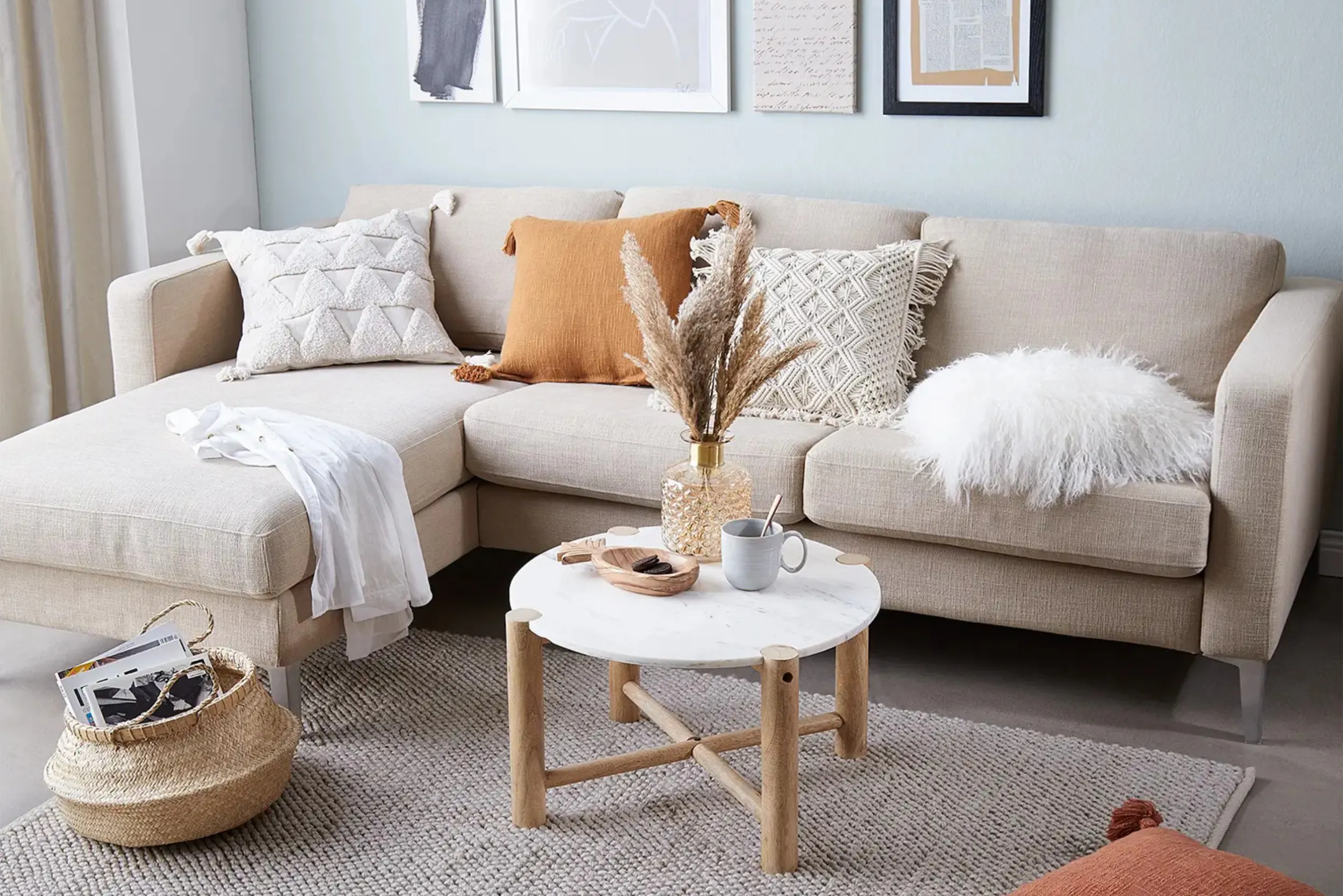 Beiges Sofa mit modernen Marmortisch vor einer hellblauen Wand