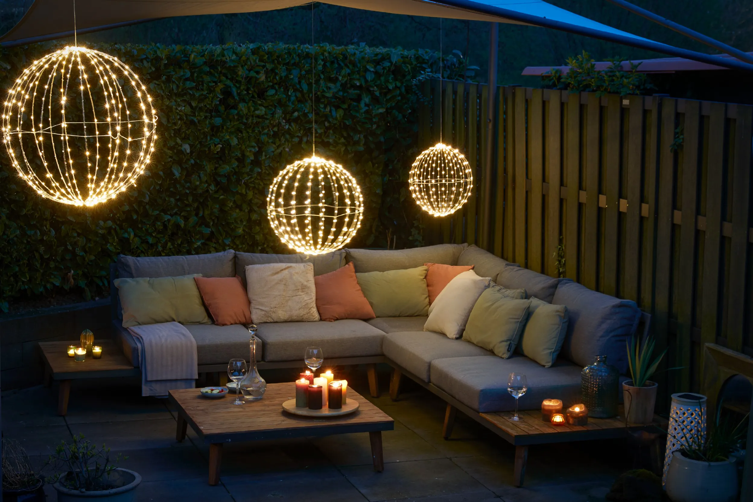 Outdoor-Lounge mit Kerzen, Laternen und hängenden Leuchtkugeln